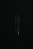 A black utility knife with a visible metal blade is placed upright against a dark background, highlighting its sleek and modern design.