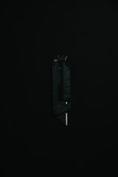 A black utility knife with a visible metal blade is placed upright against a dark background, highlighting its sleek and modern design.