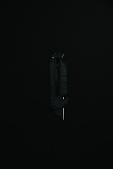 A black utility knife with a visible metal blade is placed upright against a dark background, highlighting its sleek and modern design.