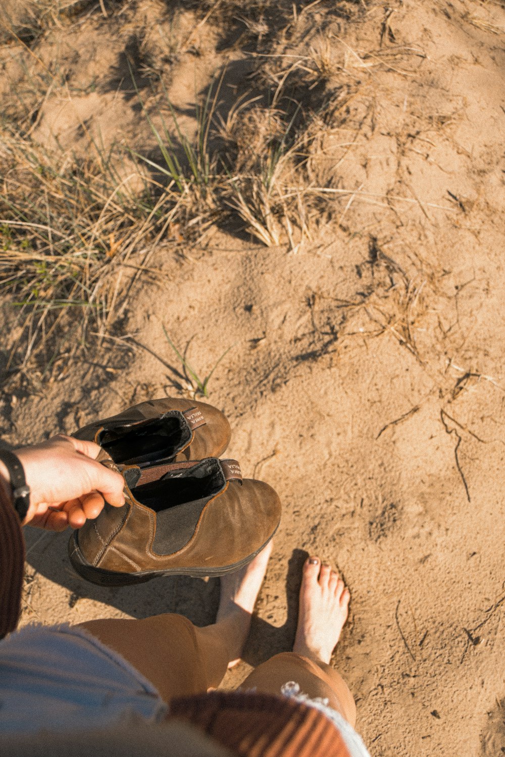 person in brown pants sitting on brown sand during daytime