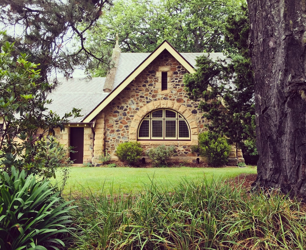 brown brick house in the middle of green grass field