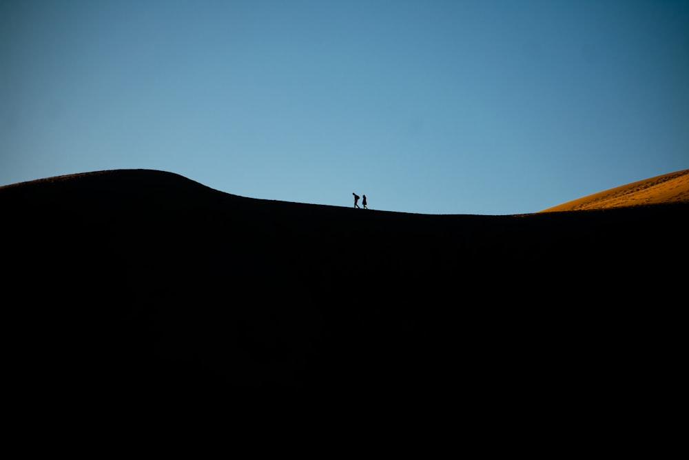 silhouette of person standing on top of mountain during daytime