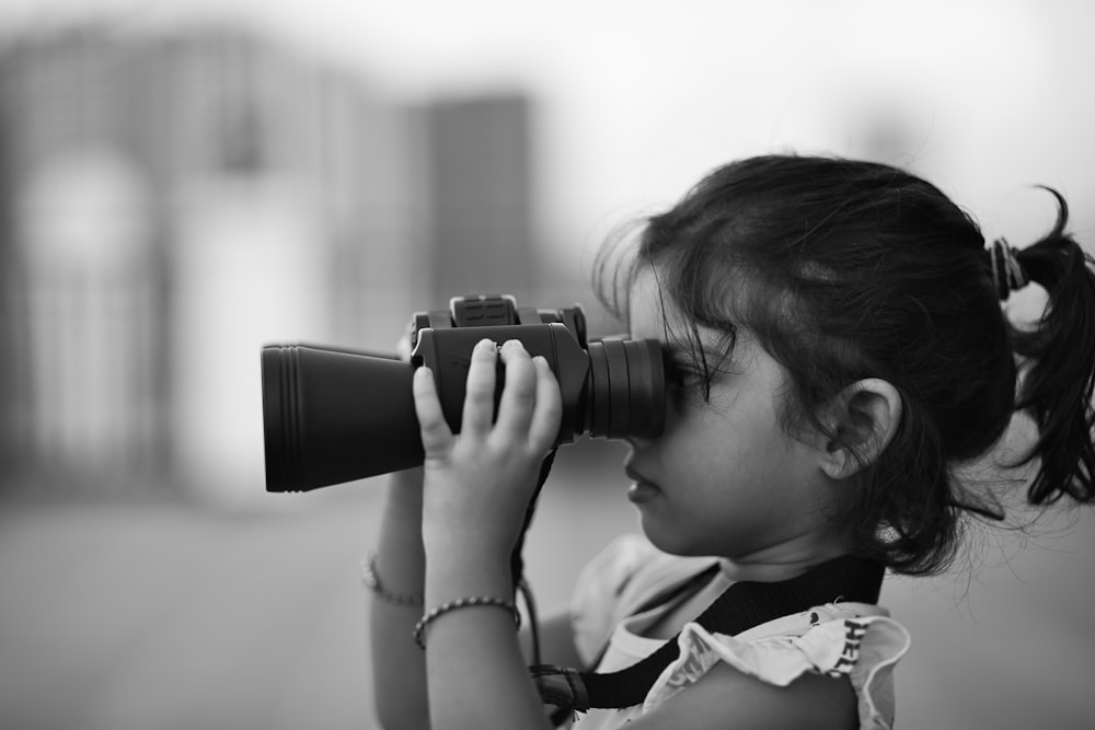 grayscale photo of child using binoculars
