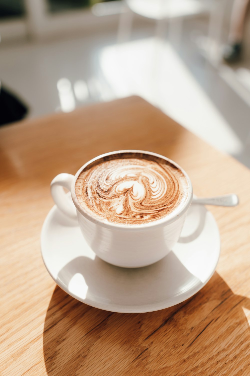 white ceramic cup with saucer on brown wooden table