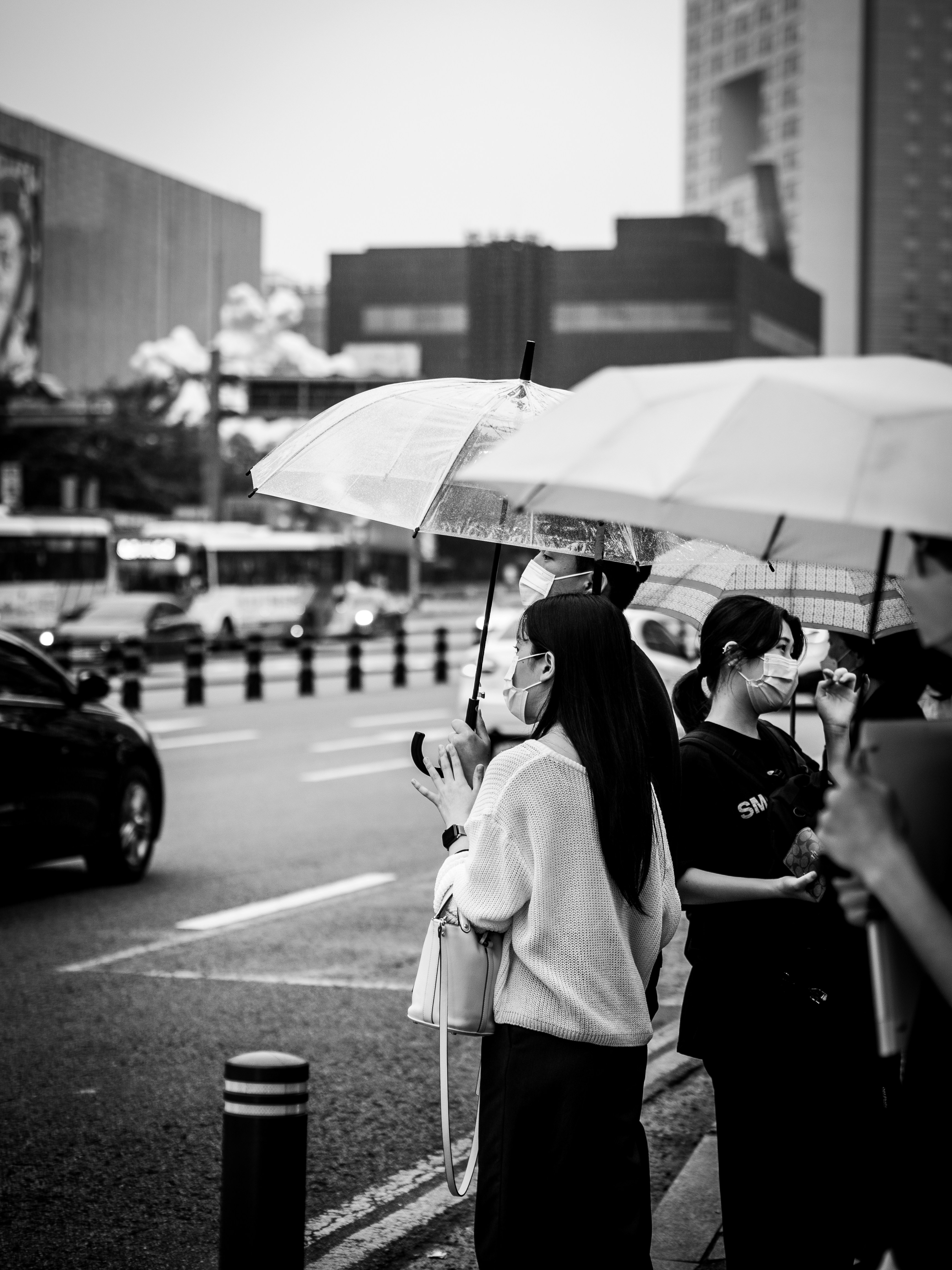 grayscale photo of woman in white coat holding umbrella