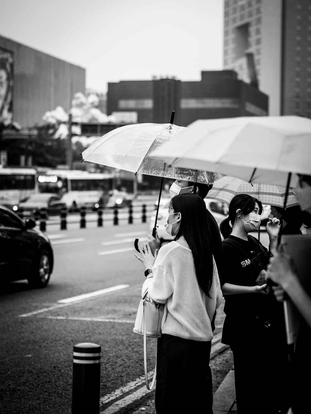 grayscale photo of woman in white coat holding umbrella