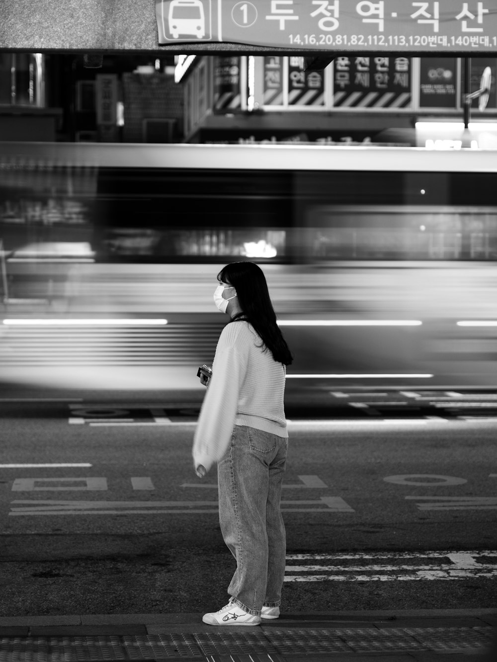 grayscale photo of woman in long sleeve shirt and pants standing on road