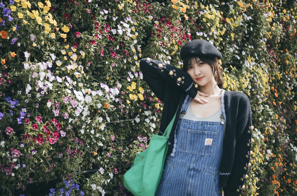 woman in blue and white striped dress and black jacket standing beside yellow flowers