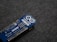 A blue Arduino MKR WiFi 1010 microcontroller board placed on a gray fabric surface. The board features numerous metal pins along one side and is marked with white text identifying its model and specifications.