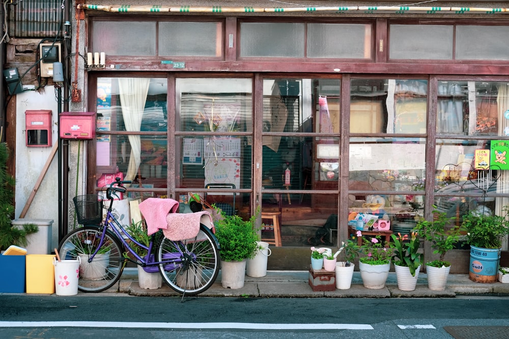 pink bicycle parked beside brown wooden store during daytime