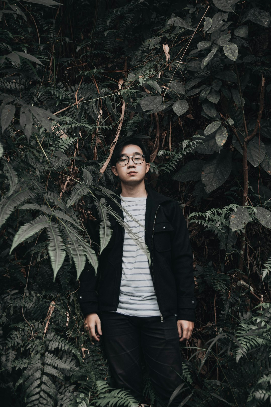 woman in black blazer standing beside green plant