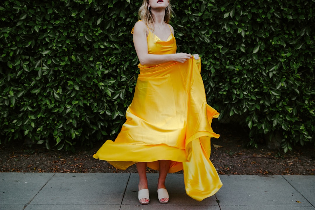 woman in yellow sleeveless dress standing on gray concrete floor
