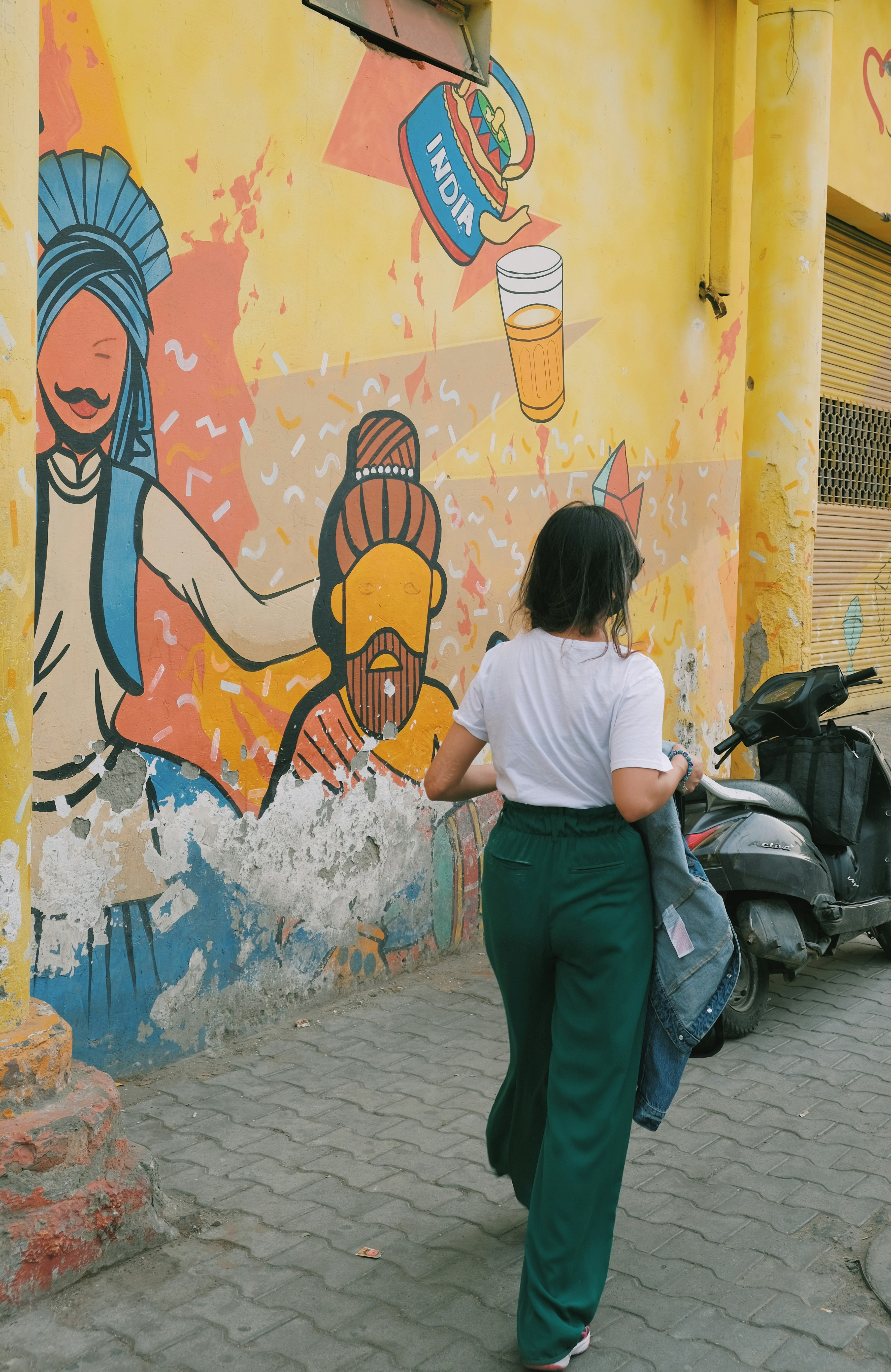 woman in white t-shirt and green pants standing beside graffiti wall during daytime