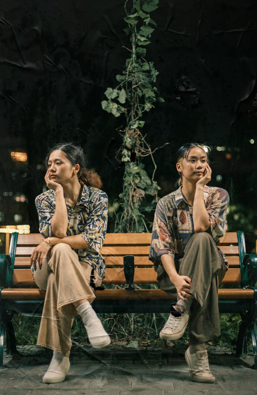 2 women sitting on brown wooden bench