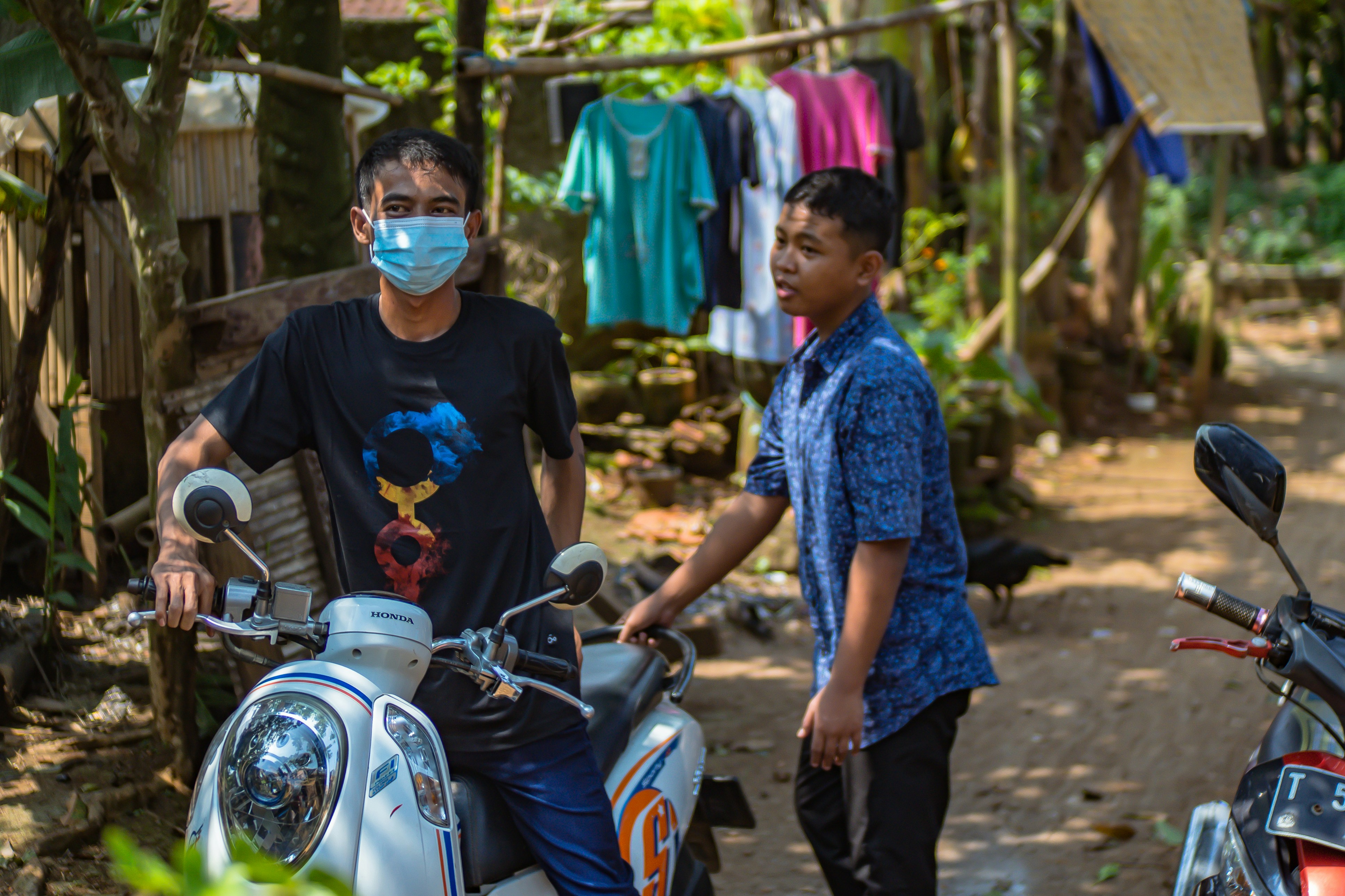 Pria berkaos leher kru biru mengendarai sepeda motor putih dan hitam di siang hari