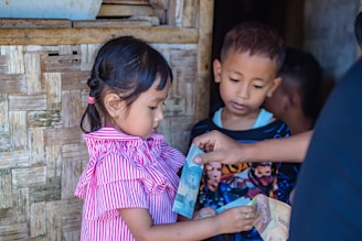 girl in pink and white stripe dress holding blue plastic bottle