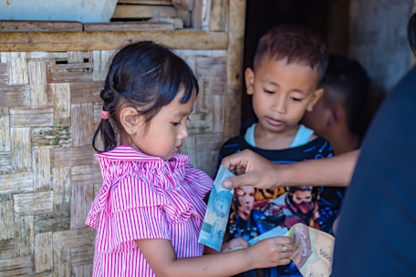 girl in pink and white stripe dress holding blue plastic bottle
