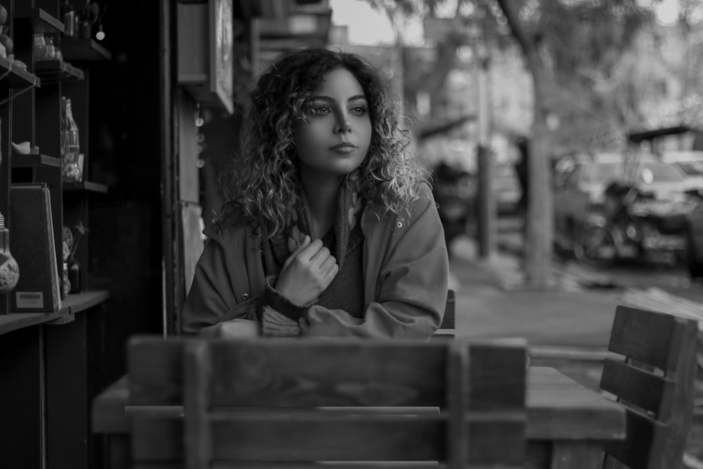 grayscale photo of woman in coat holding cup