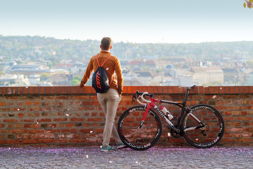 woman in red long sleeve shirt and white shorts standing beside black bicycle during daytime