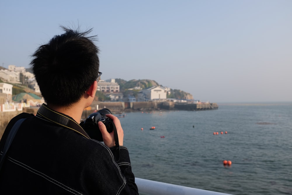 man in black leather jacket holding black smartphone