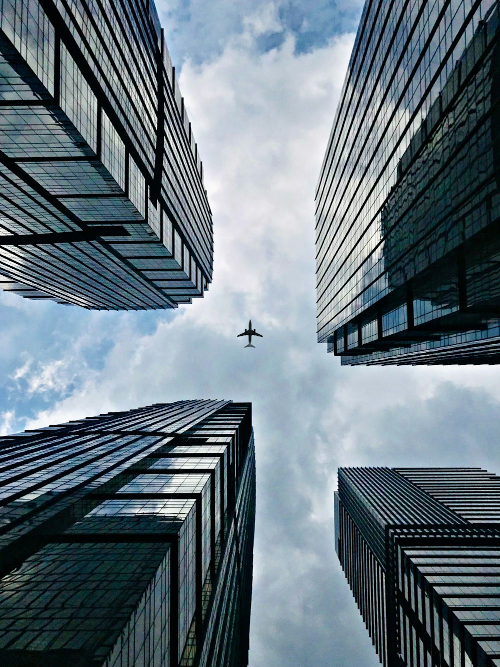 airplane flying over the high rise building during daytime