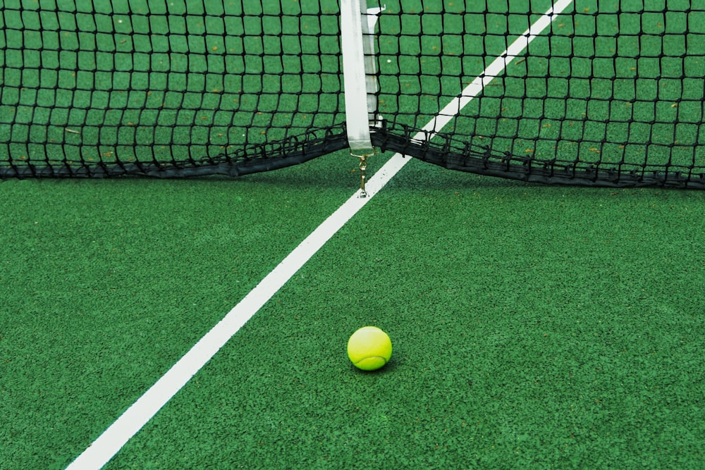 white and yellow tennis ball on green grass field