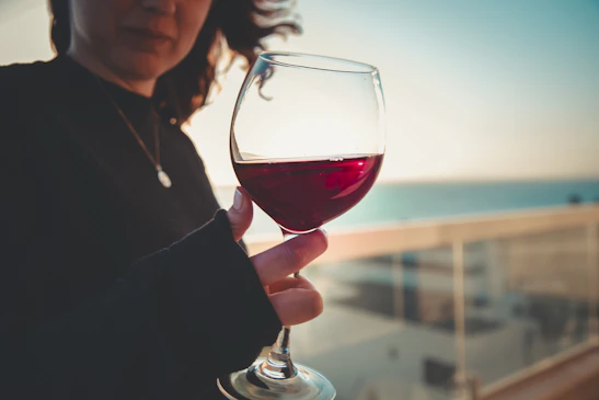 A cozy outdoor setup at the breakwall with glasses of red and white wine catching the sunset glow.