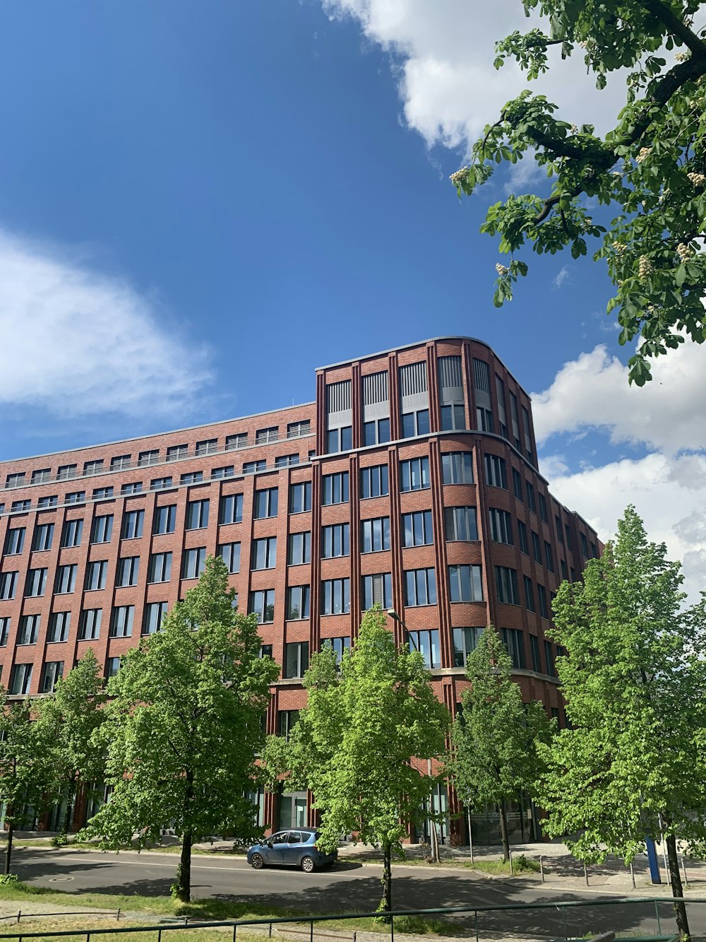 brown concrete building near green trees under blue sky during daytime