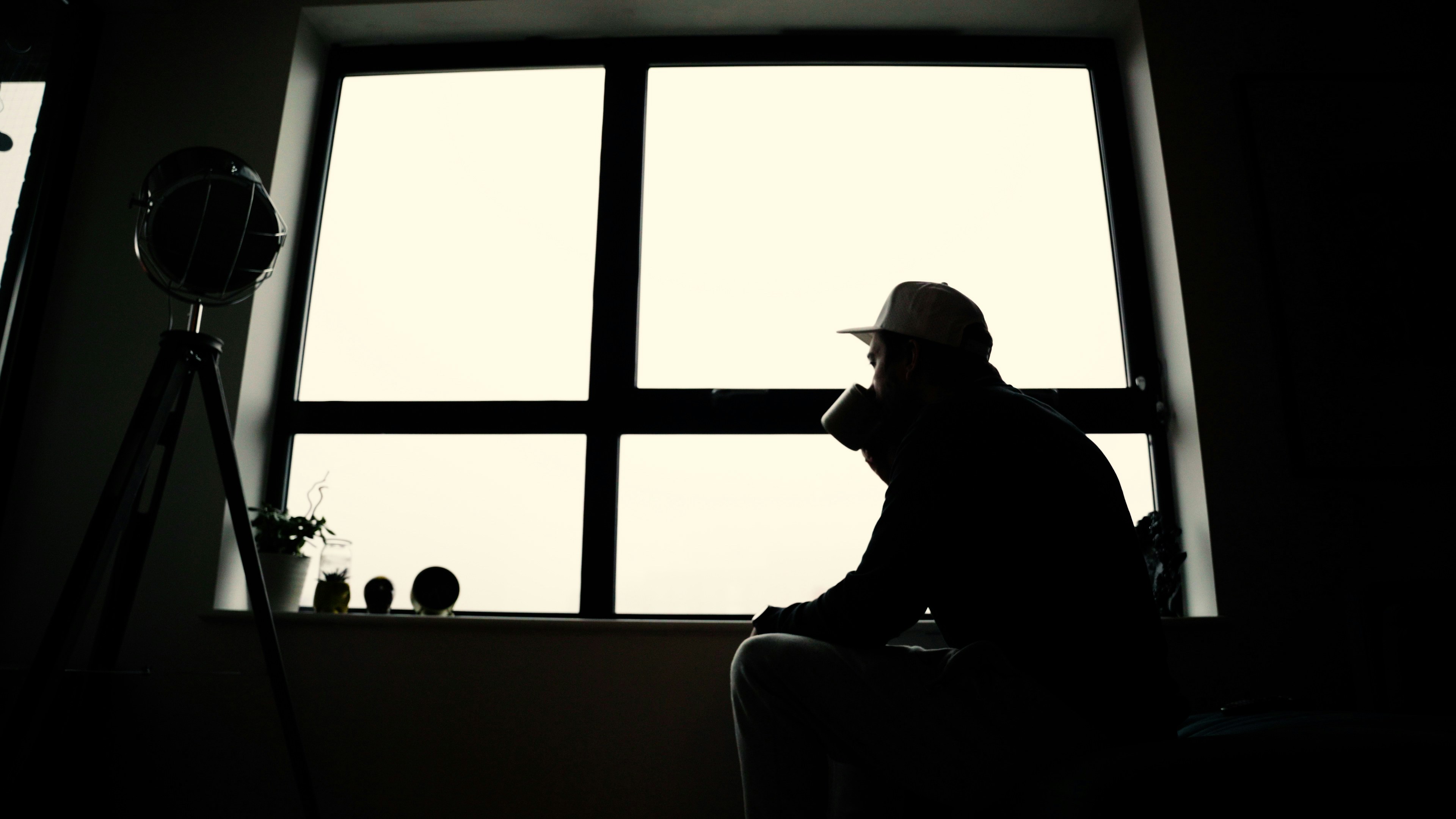 man in black jacket and black pants sitting on brown couch