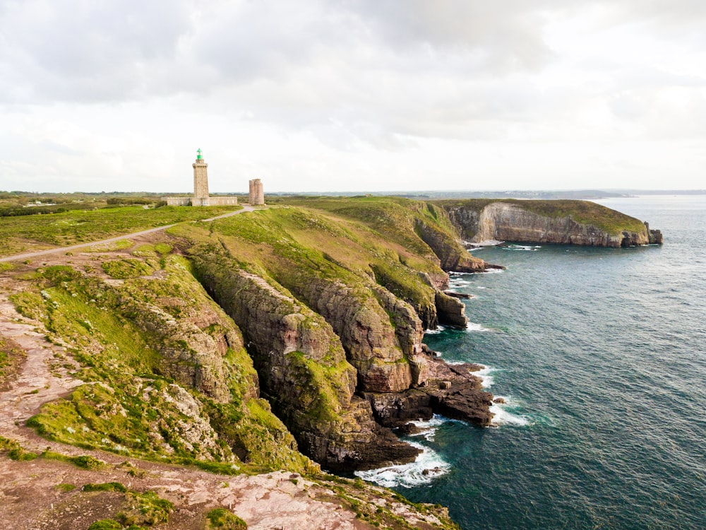 white lighthouse on cliff beside sea during daytime