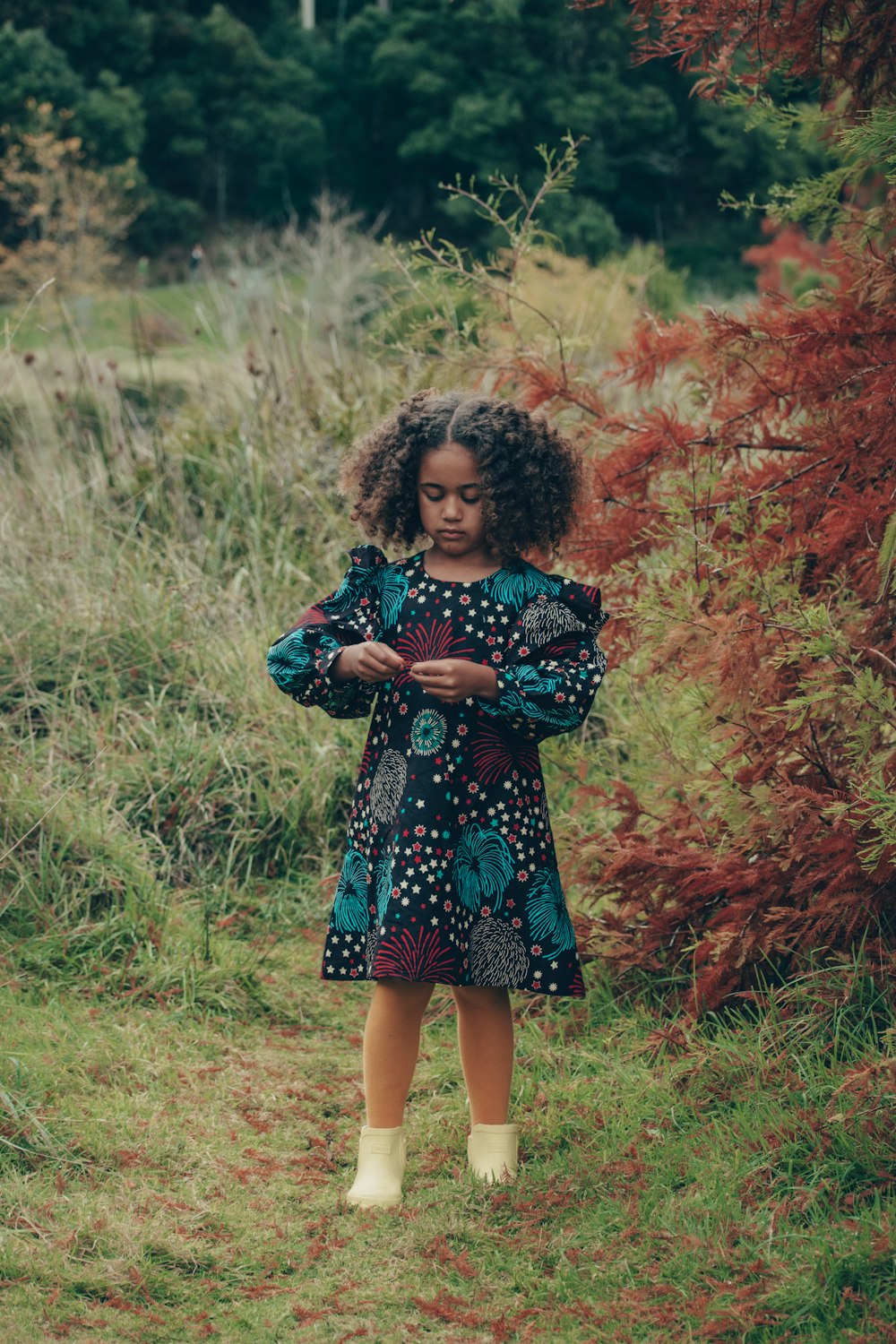 girl in blue and white floral dress standing on green grass field during daytime