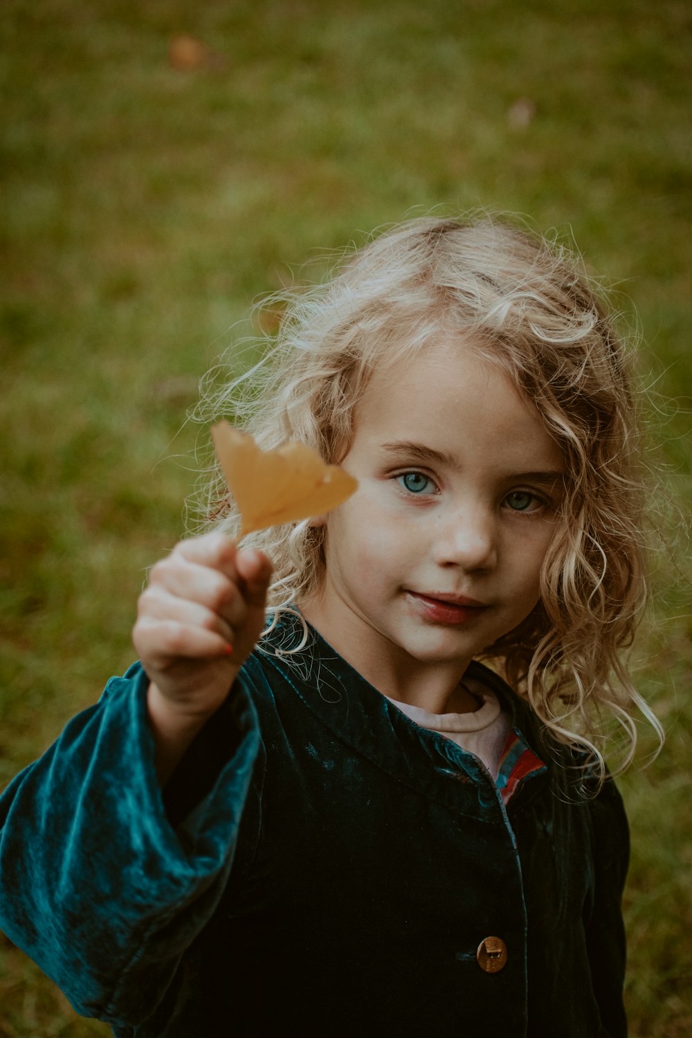 girl in blue and black shirt holding orange carrot