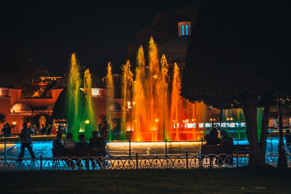 people sitting on bench near fountain during night time
