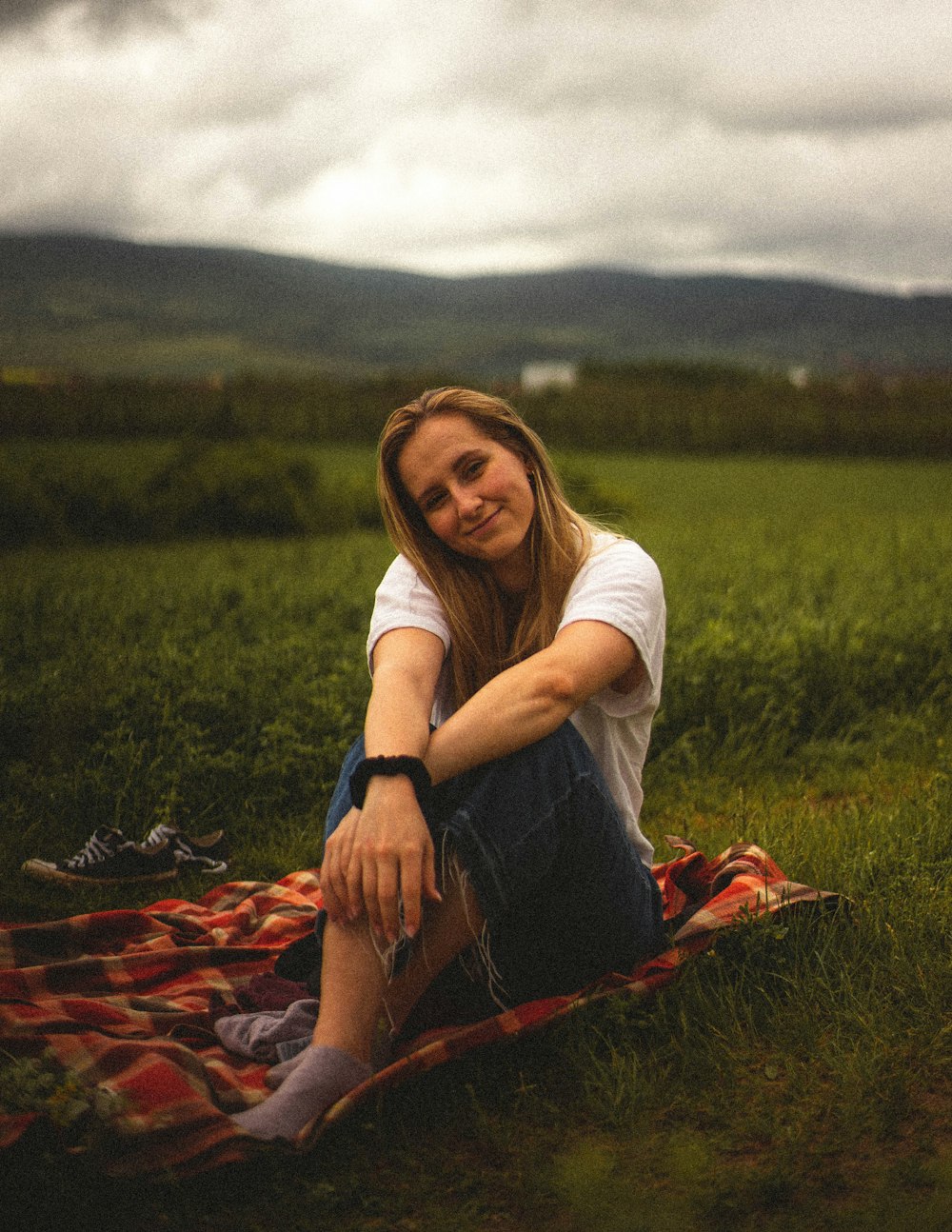 woman in white shirt and blue denim jeans sitting on ground