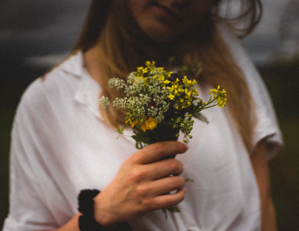 woman in white shirt holding yellow flower bouquet