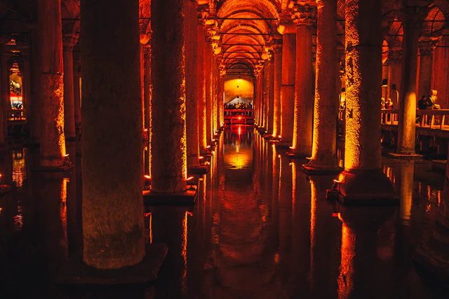 Rows of stone columns rise from the dark water of the Basilica Cistern, lit amber.