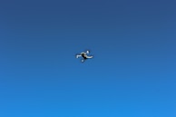 Close-up of a drone in flight against a clear blue sky.