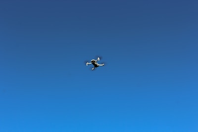 Close-up of a drone in mid-flight against a clear blue sky.
