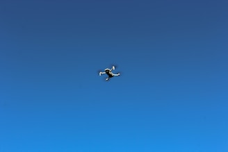 Close-up of a drone in flight against a clear blue sky.