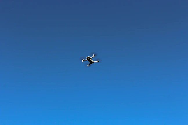 Close-up of a sleek drone hovering against a clear blue sky.