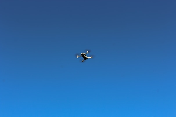 A sleek drone prototype hovering against a clear blue sky.