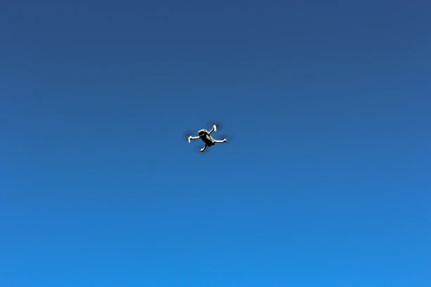 Close-up of a drone in mid-flight against a clear blue sky.
