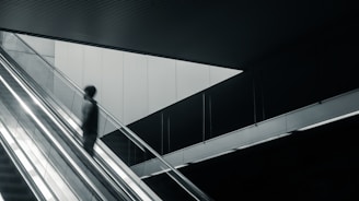 Movers carefully carrying furniture down the stairs in a modern Barcelona building.