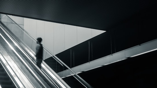 Movers carefully carrying furniture down the stairs in a modern Barcelona building.