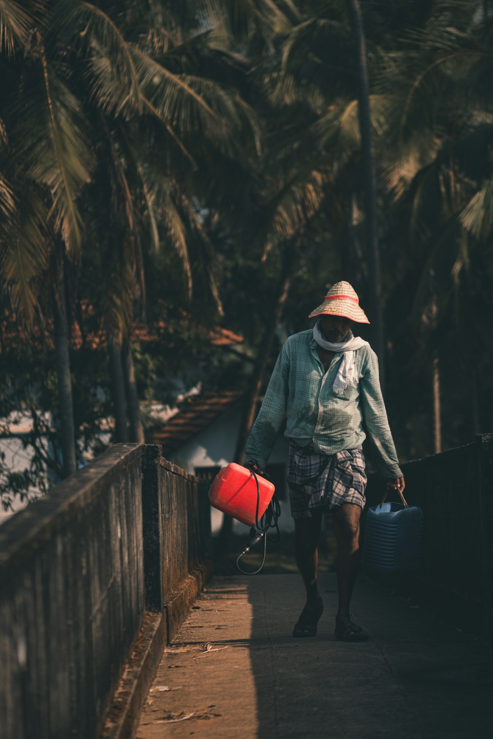 woman in gray jacket and black pants holding red sling bag walking on wooden bridge during