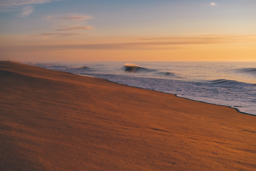 sea waves crashing on shore during sunset