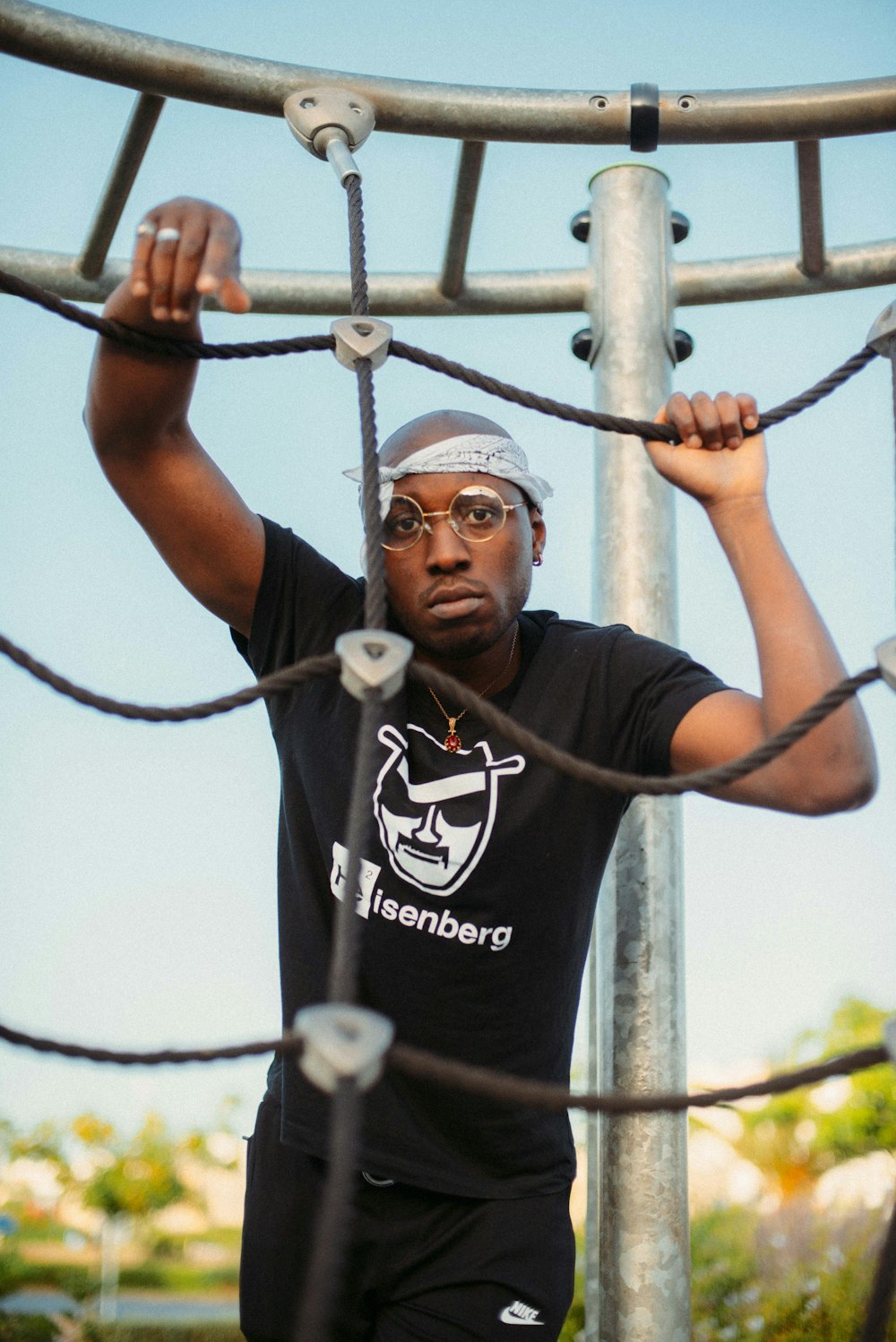 T-shirt noir à col rond noir tenant sur une barre de métal gris pendant la journée