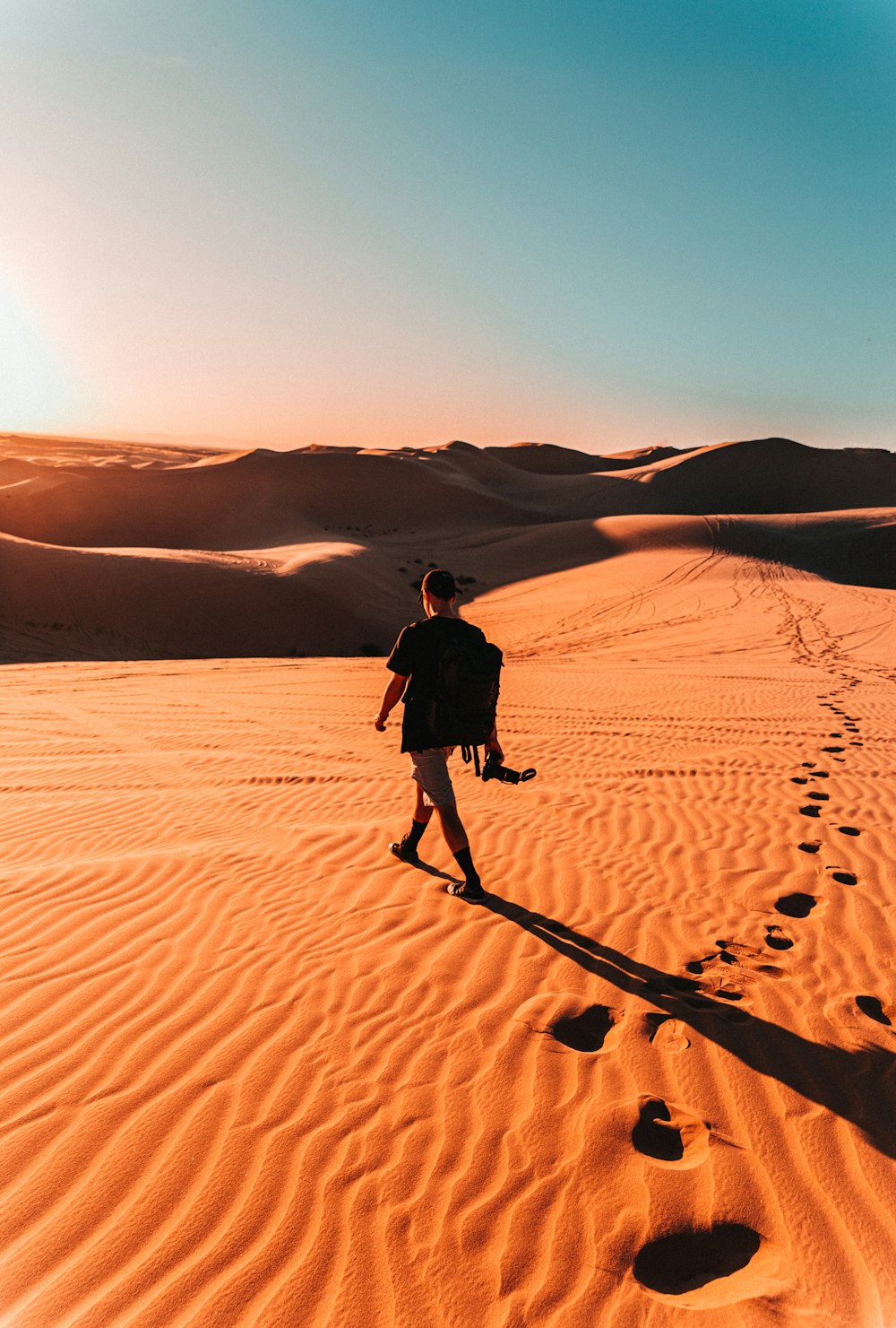 man in black jacket walking on desert during daytime