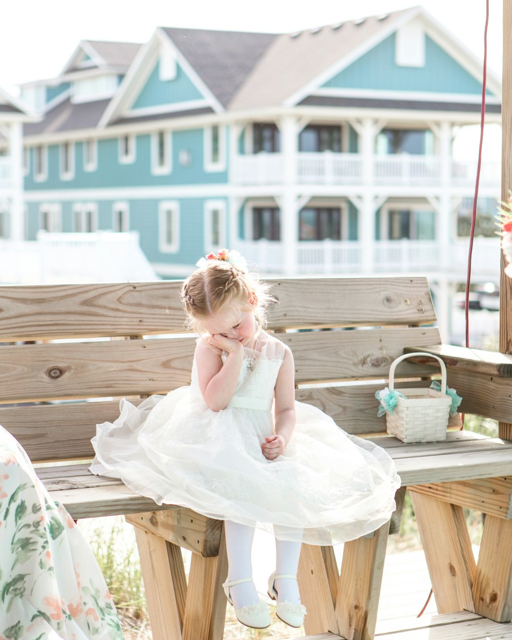 girl in white dress sitting on brown wooden bench during daytime