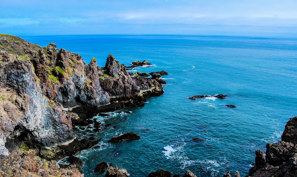 green and brown rock formation on sea during daytime